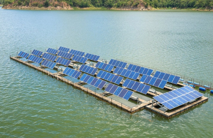 Solar panels are suspended calmly on the water's surface & reflect sunlight when mounted on a floating pier